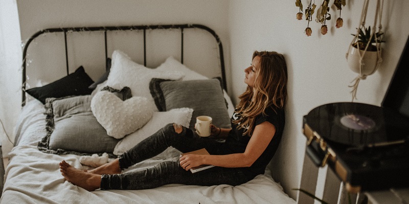 ベッドの上でコーヒーを飲む女性